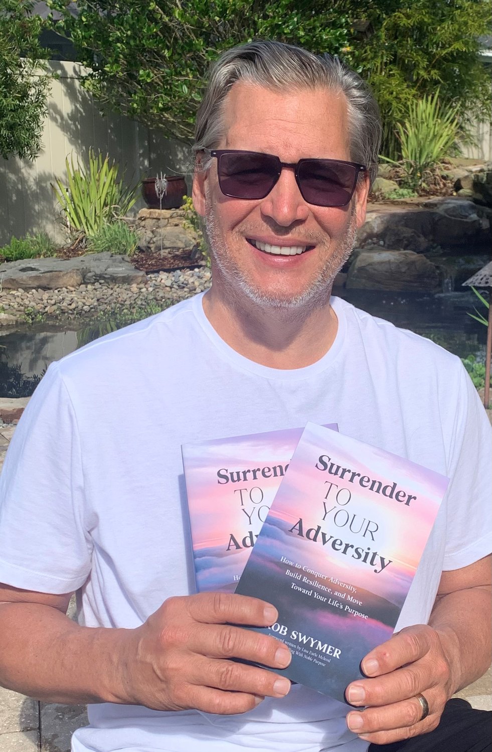 Rob Swymer holds up copies of his book, “Surrender to Your Adversity.”